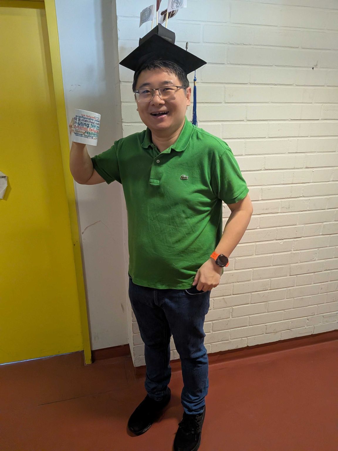 Wenkai Dai wearing a graduation cap and holding a thesis-themed sign after his PhD defense